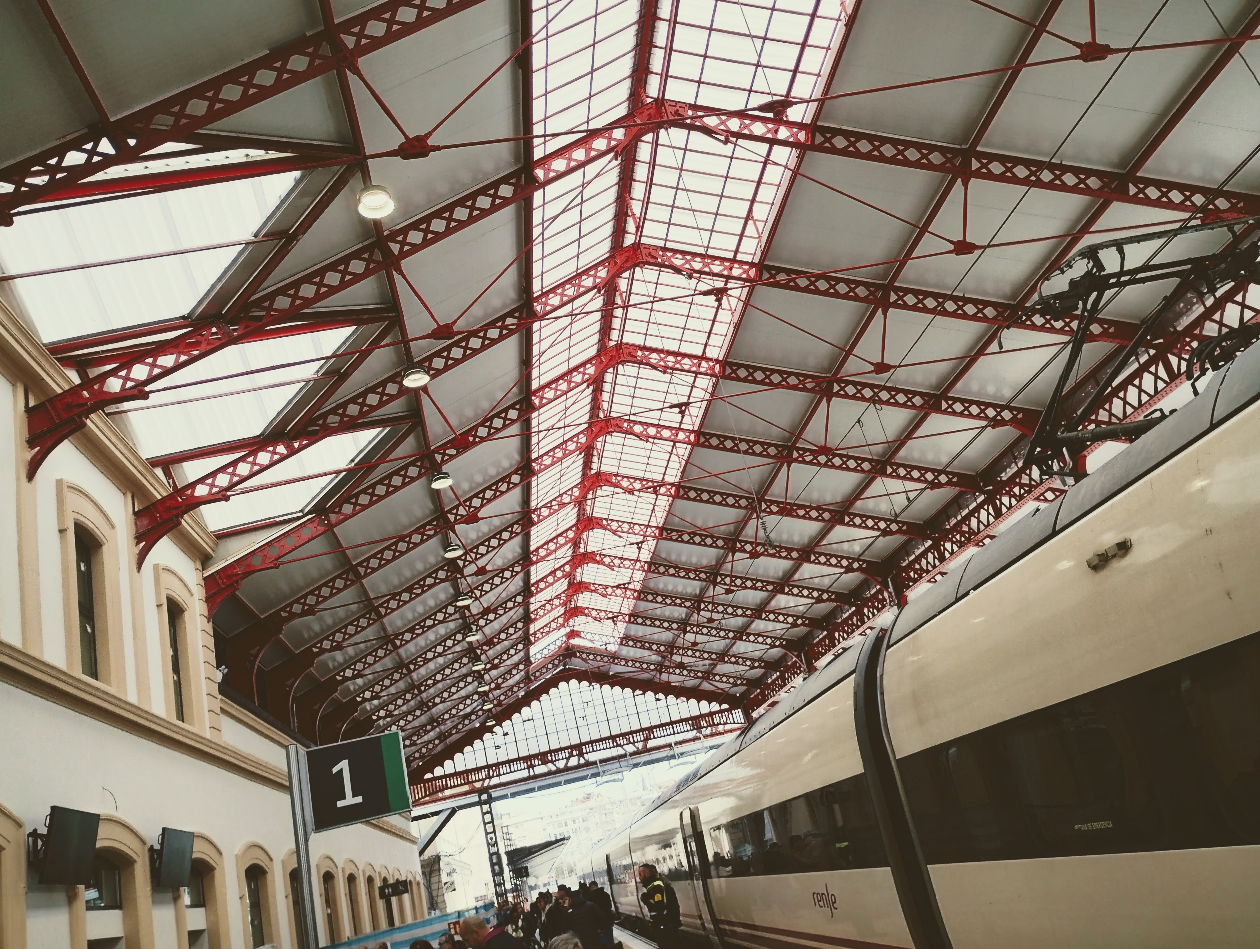 A Spanish high-speed trainer under the metal train shed roof at Donostia San Sebastián railway station.