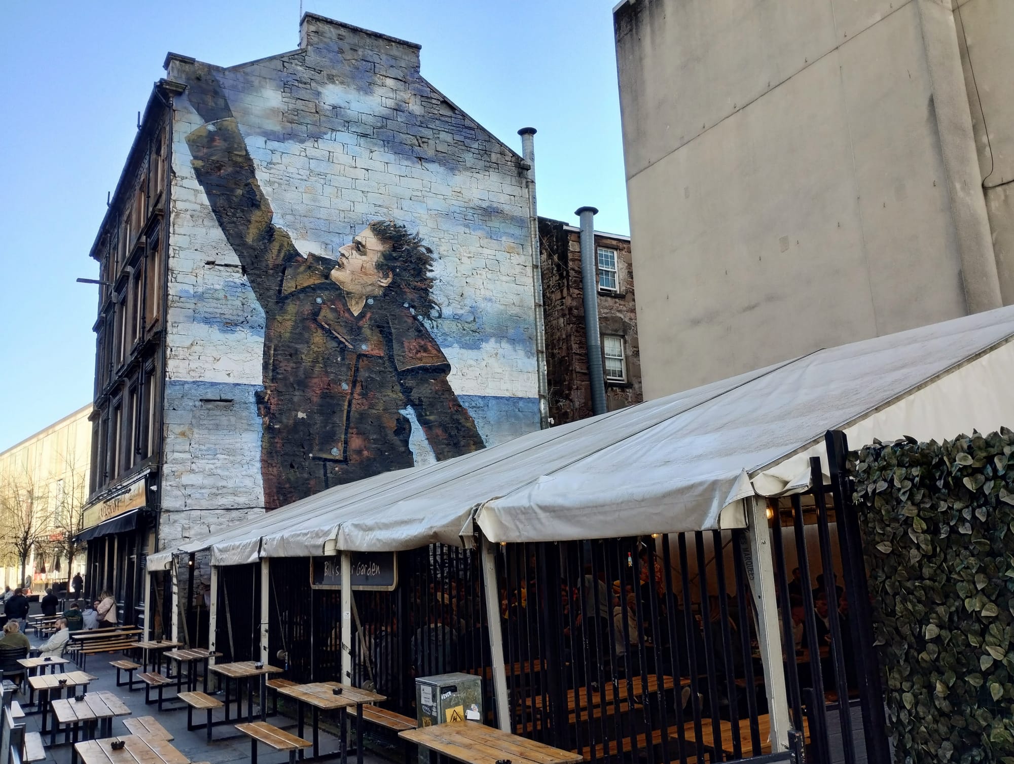 A mural of Billy Connolly on an end wall of a pub.