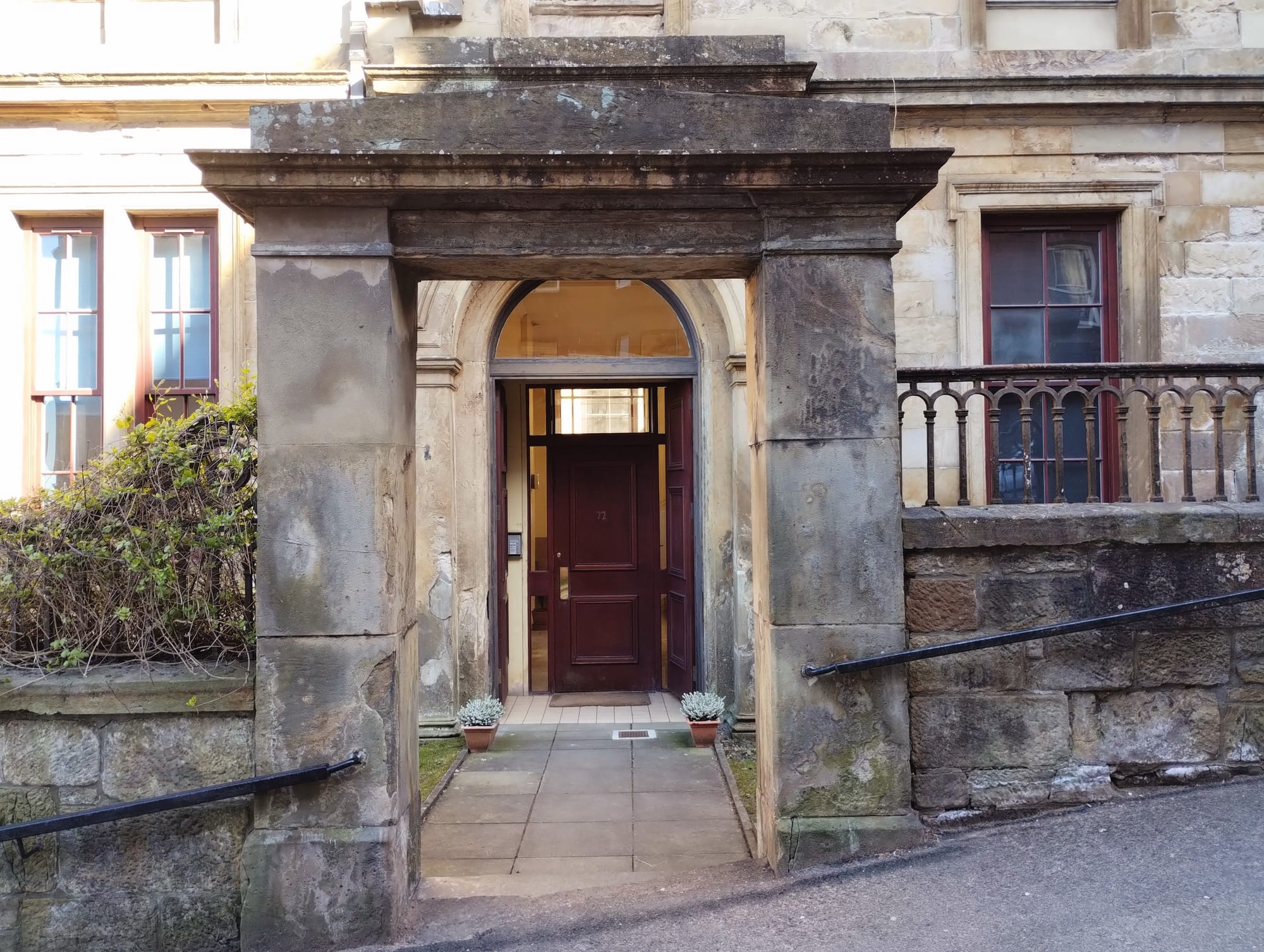A modern wooden door as seen through a stone arch.