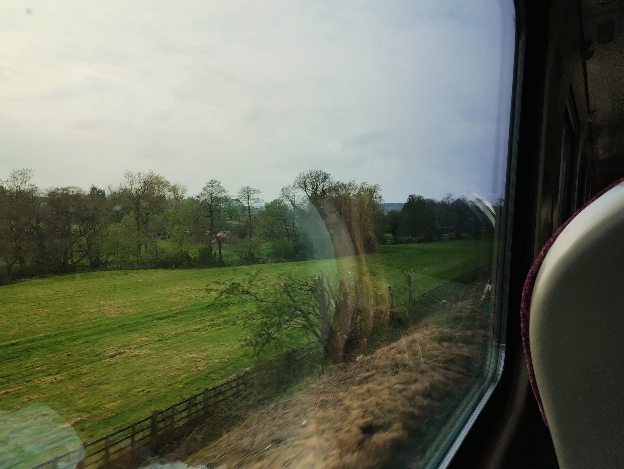 Green fields pass a train window.