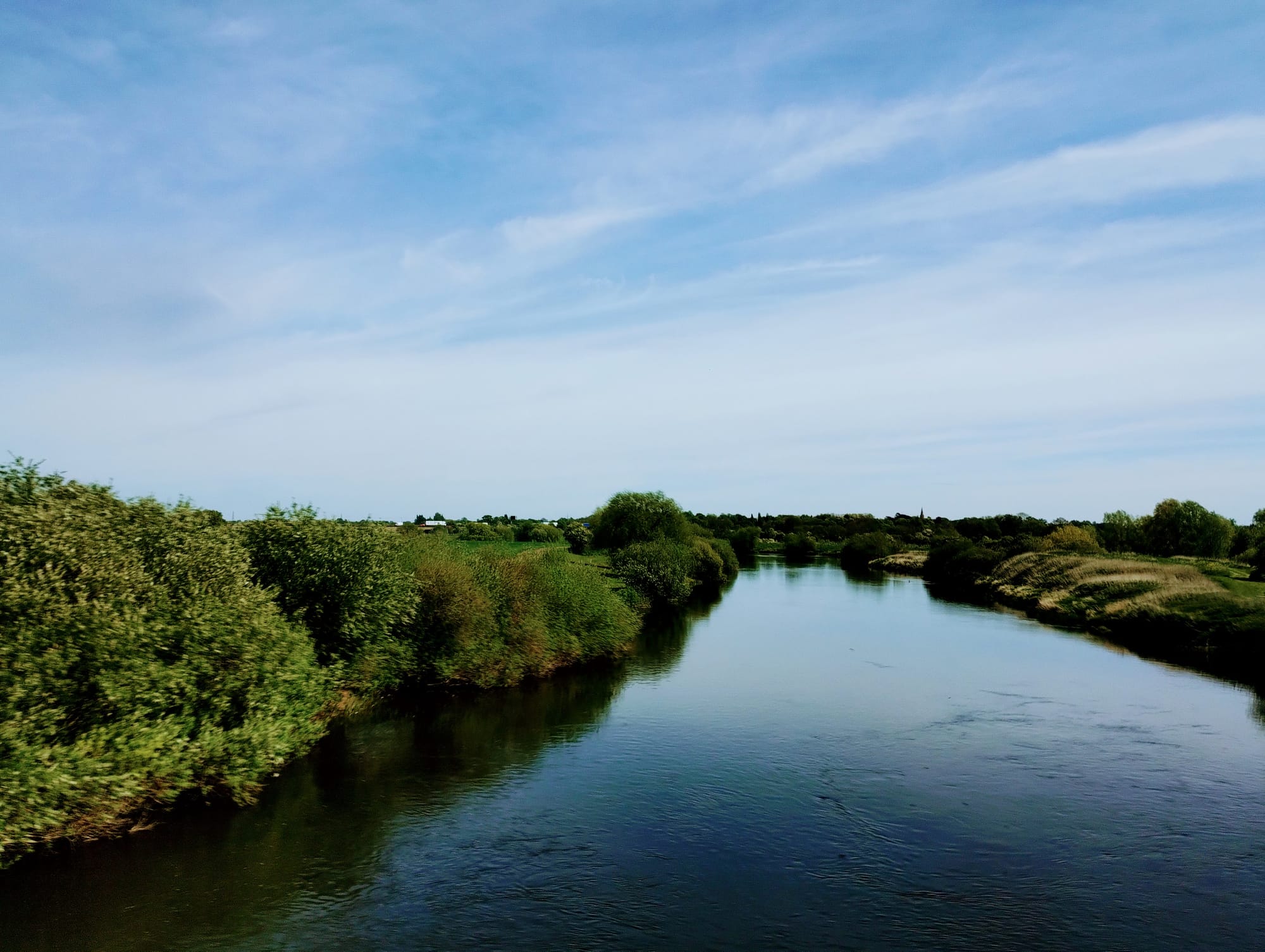 A river flows to the horizon through green wooded banks.
