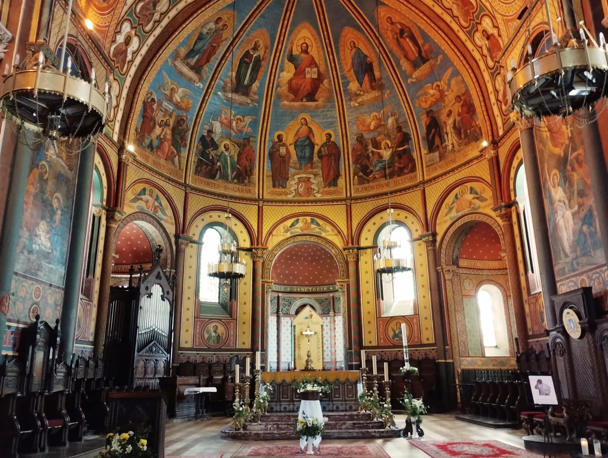 Interior view of the chancel of Agen Cathedral, showcasing its Romanesque apse, Gothic nave, and vibrant frescoes depicting biblical scenes.