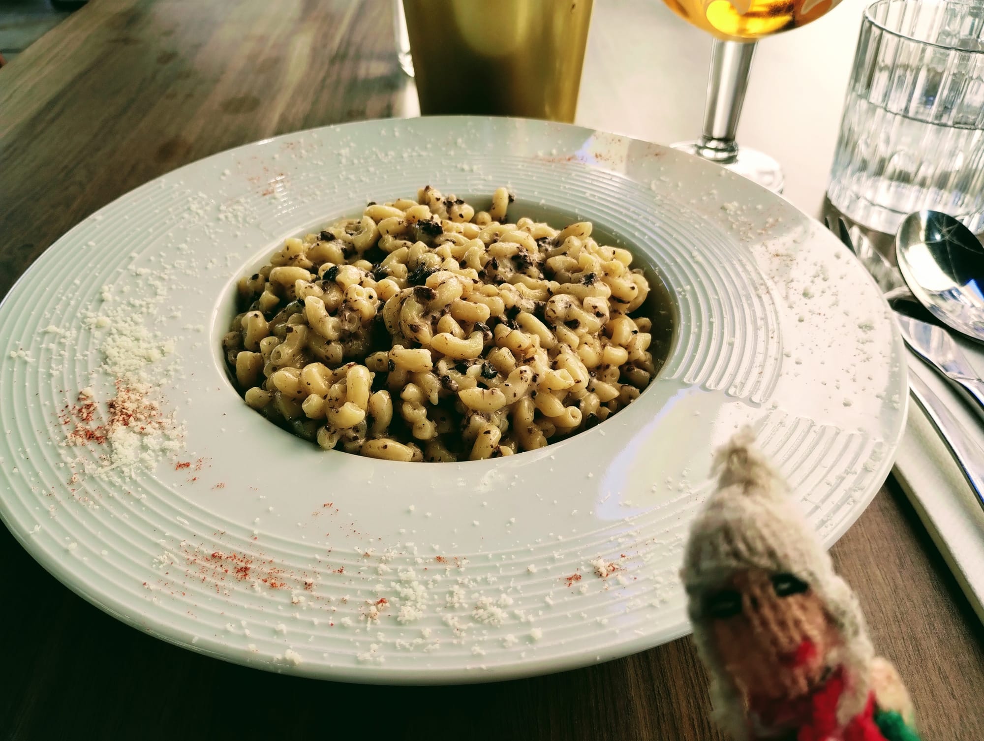 Finger puppet in front of a large dish of small pasta with truffles and parmesan.