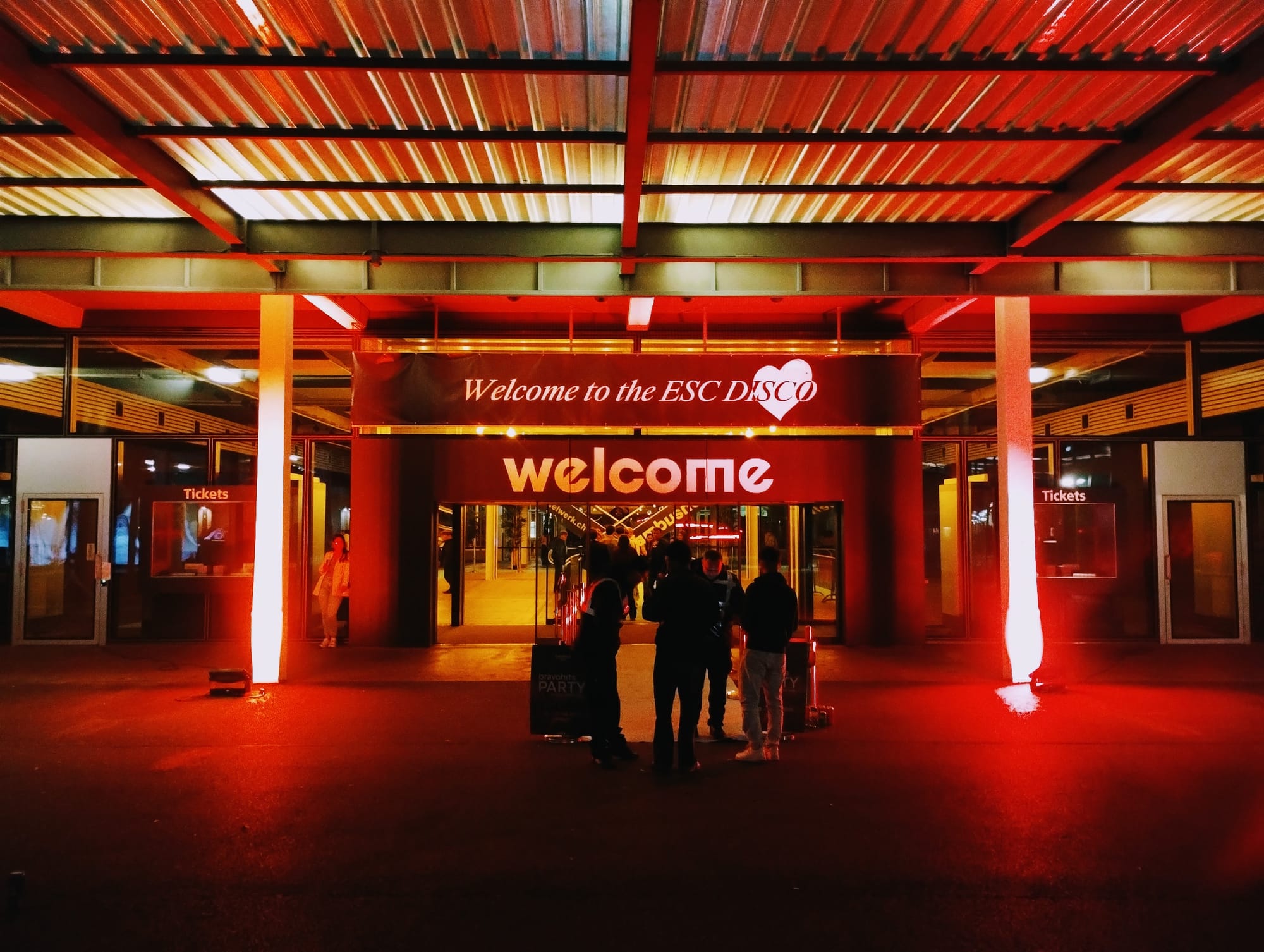 A group of four people at the entrance to the ESC Disco in the Eurovision village.