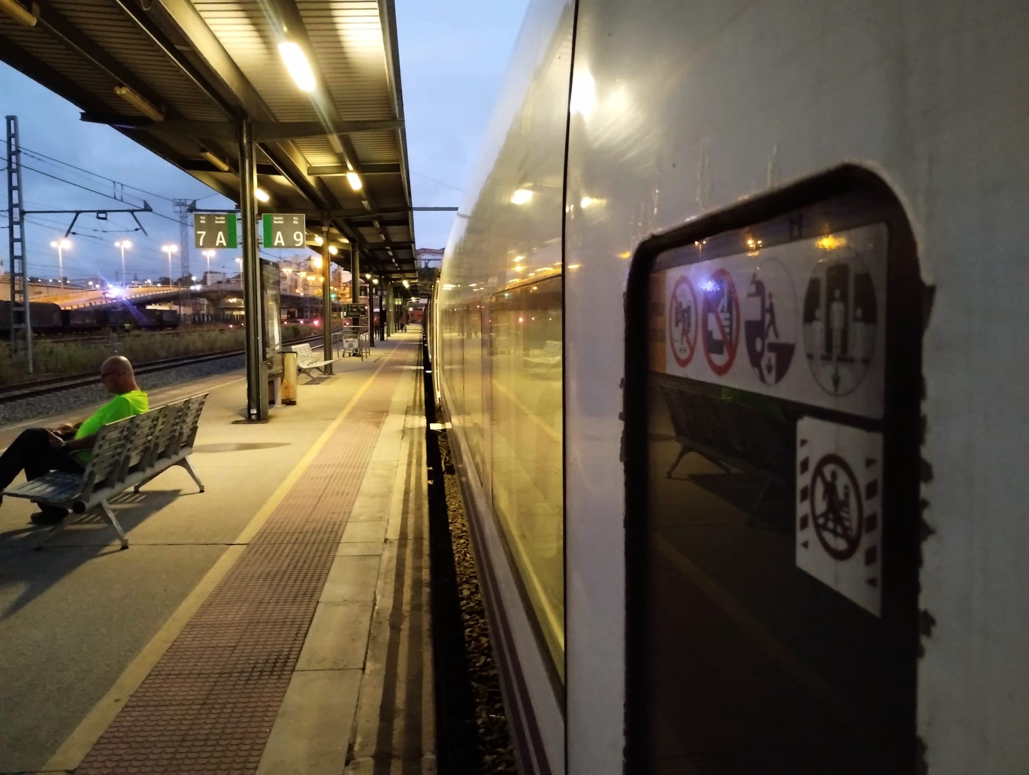View along the length of a train waiting on platform 9 at Vigo Guixar railway station at dawn.
