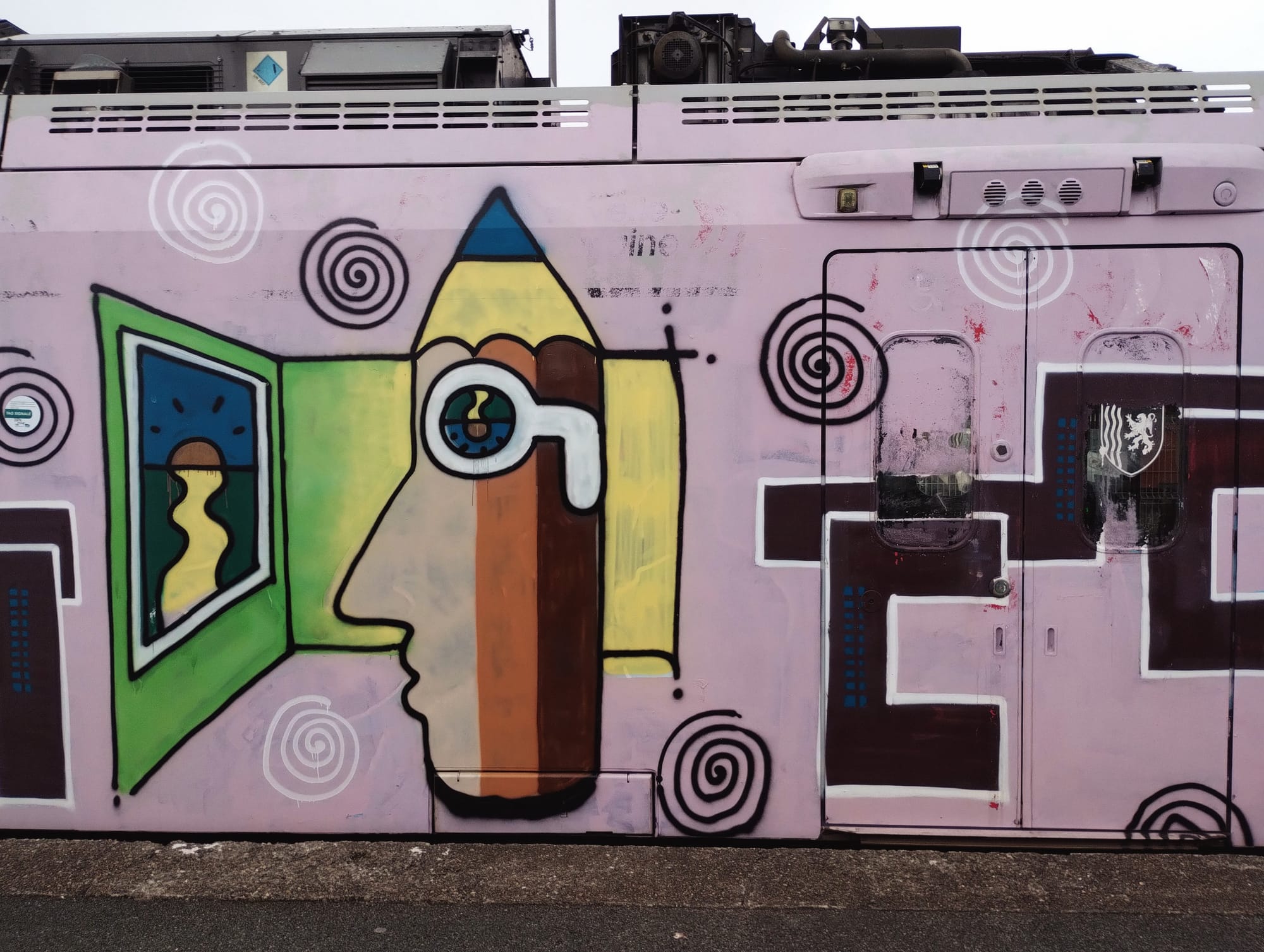 Side of a TER painted pink and covered with graffiti. The art includes a profile of a face made of a pencil shape, with an eye shaped like an ink well looking into a window showing a yellow road to the setting sun. The right has a dark panel with white lines outlining geometric shapes.