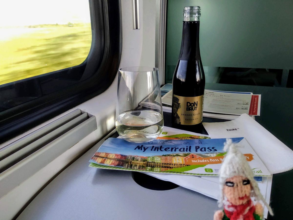 A Peruvian finger puppet on a train with a bottle of Don Brut champagne and an Interrail pass.
