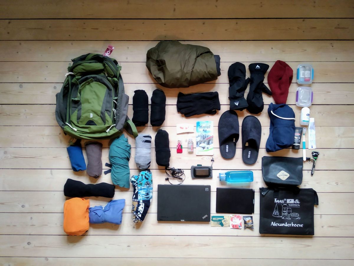 Puppet among the assorted contents of a 5.11 Covrt 18 2.0 backpack on a light wooden floor.