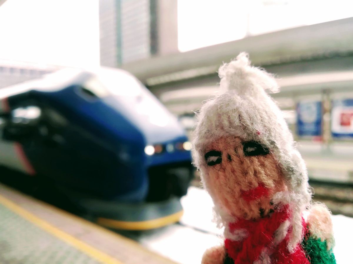 A finger puppet waiting at the pointy end of a blue train in Oslo.