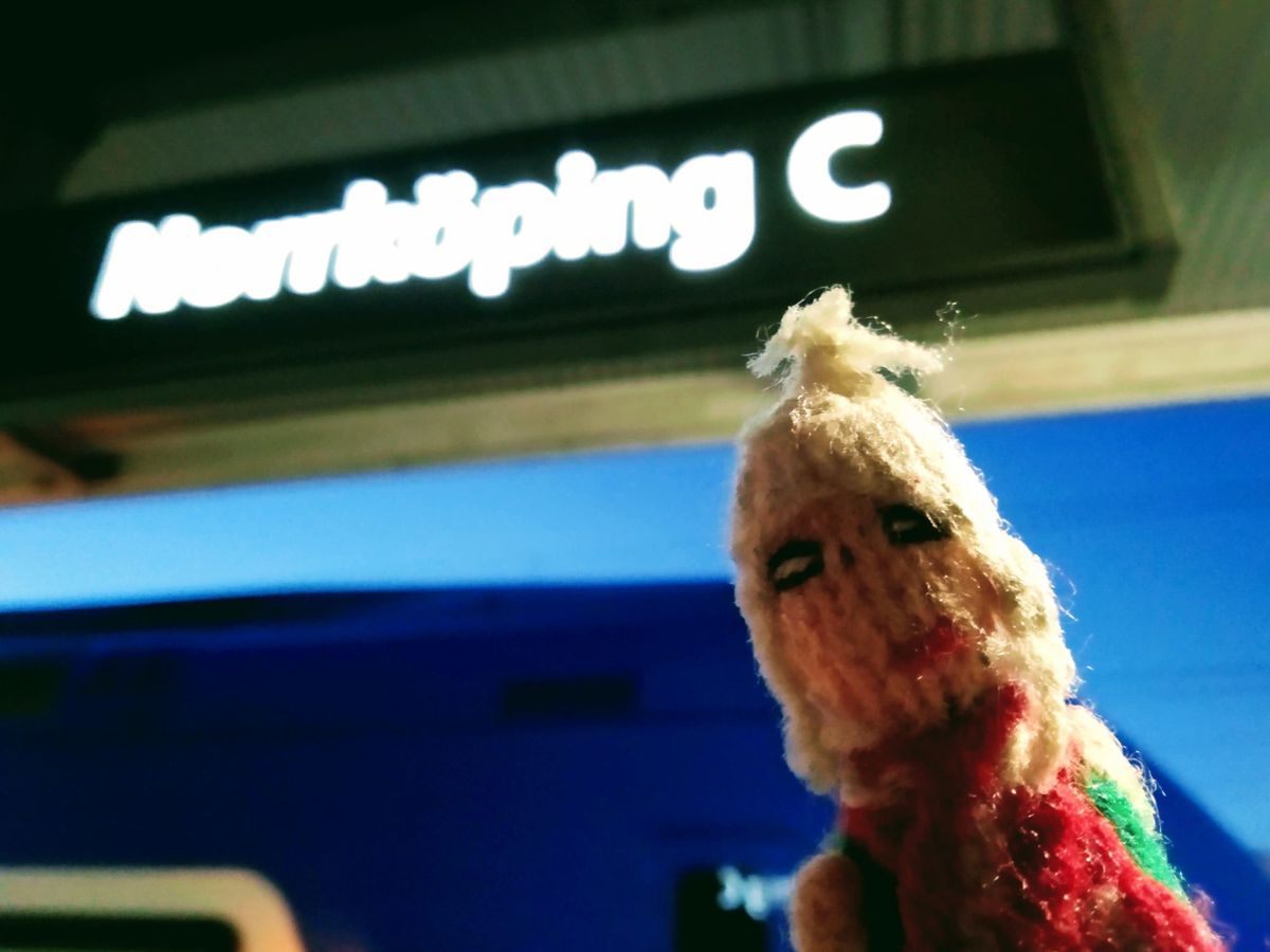 Underneath an illuminated platform sign at Norrköping C, a finger puppet tries to keep his extremities warm.