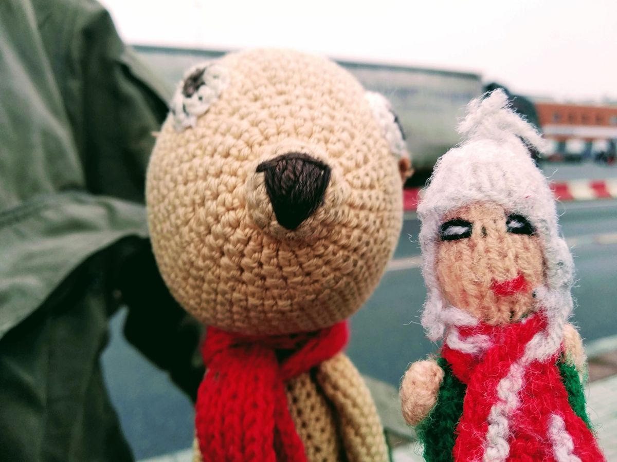 A slightly nervous finger puppet making friends with a knitted muskrat, both wearing a red scarf.