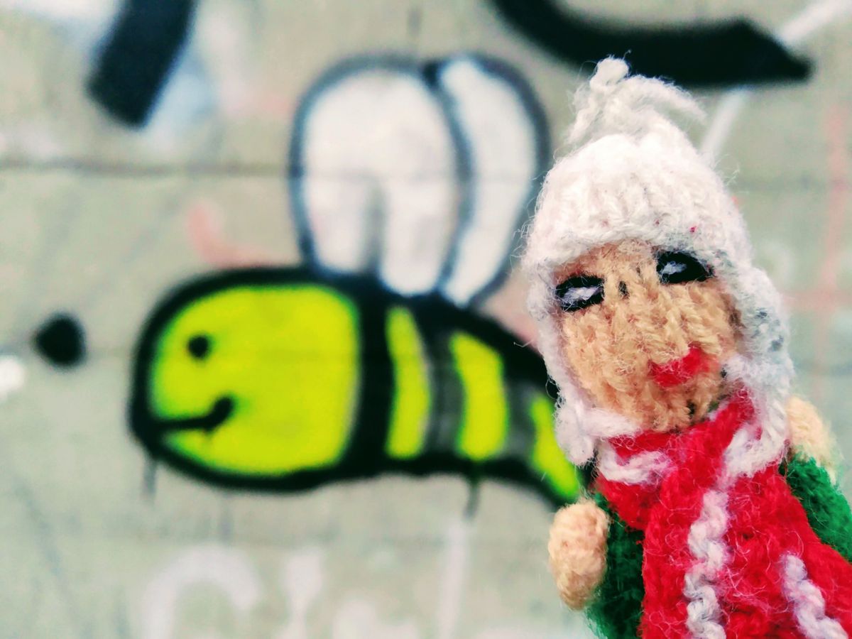Finger puppet in front of a smiling graffiti bee.