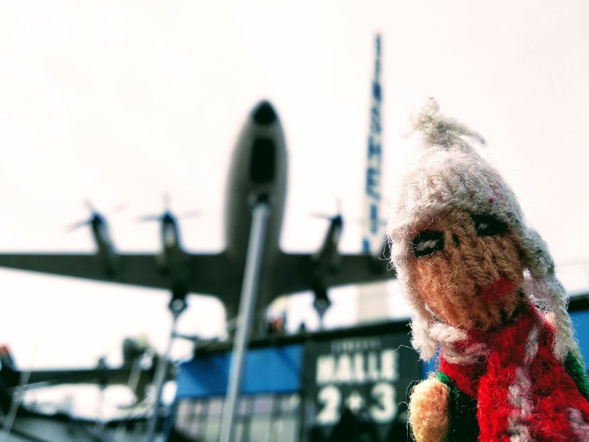 Finger Puppet cosplays Biggles underneath a preserved aeroplane at the entrance to the Sinsheim Technikmuseum.