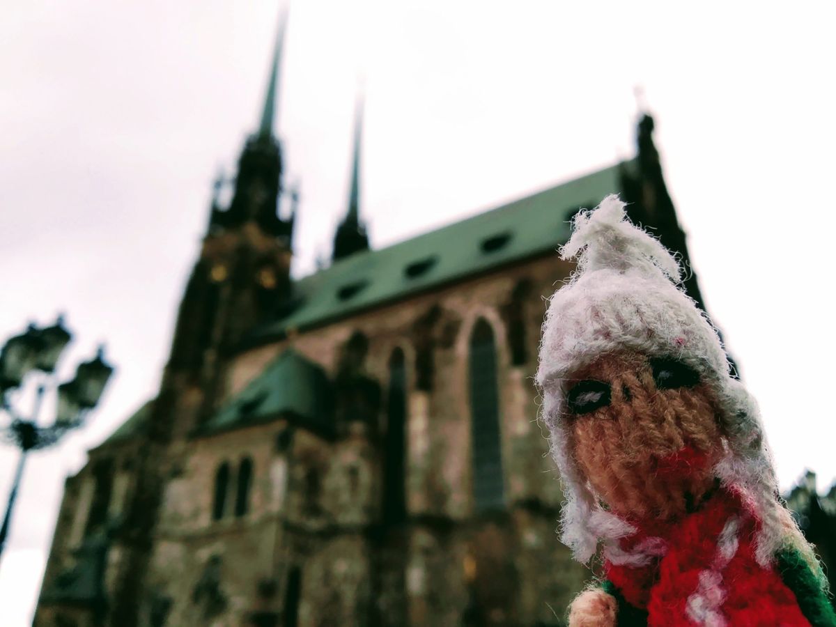 Finger puppet standing outside a massive Gothic church.