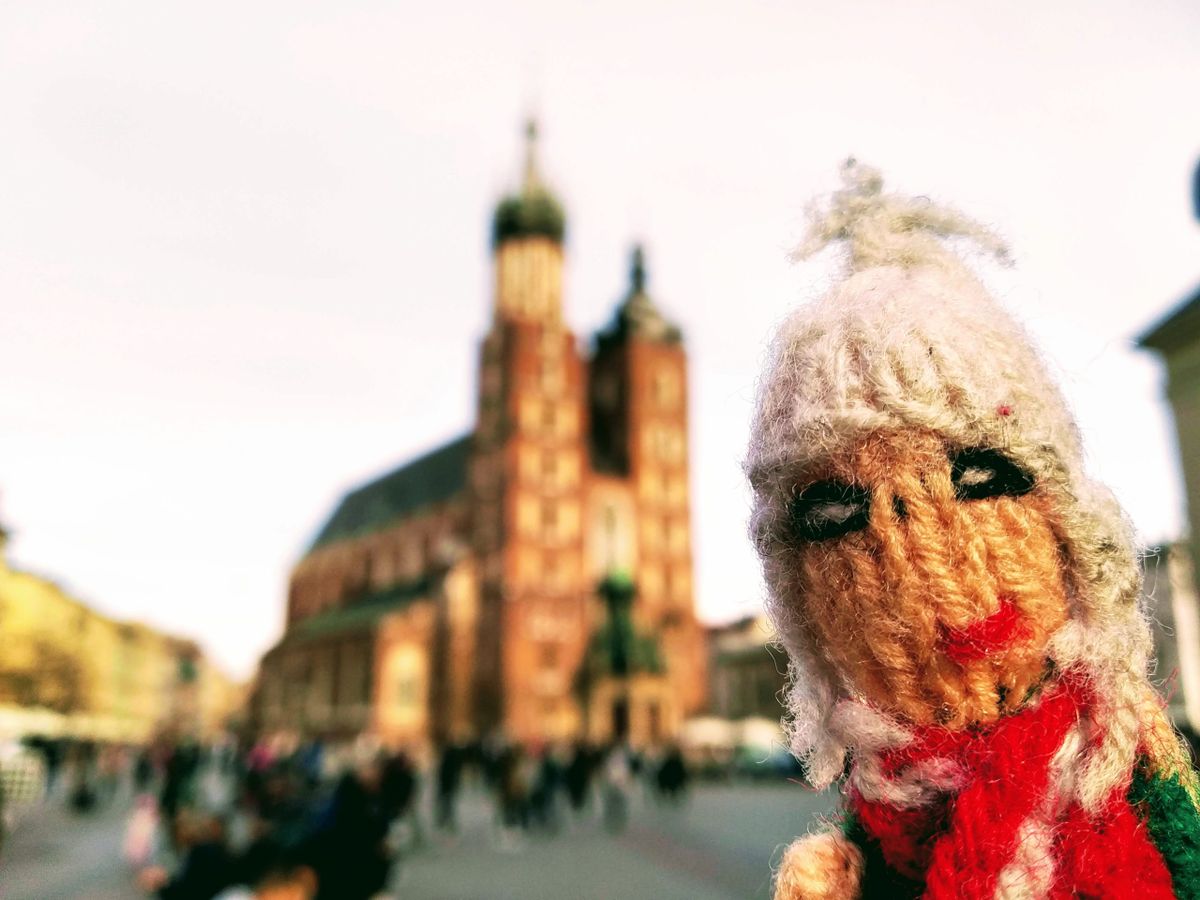 A blurry picture of St. Mary's Basilica in Kraków is made better by the presence of a finger puppet.