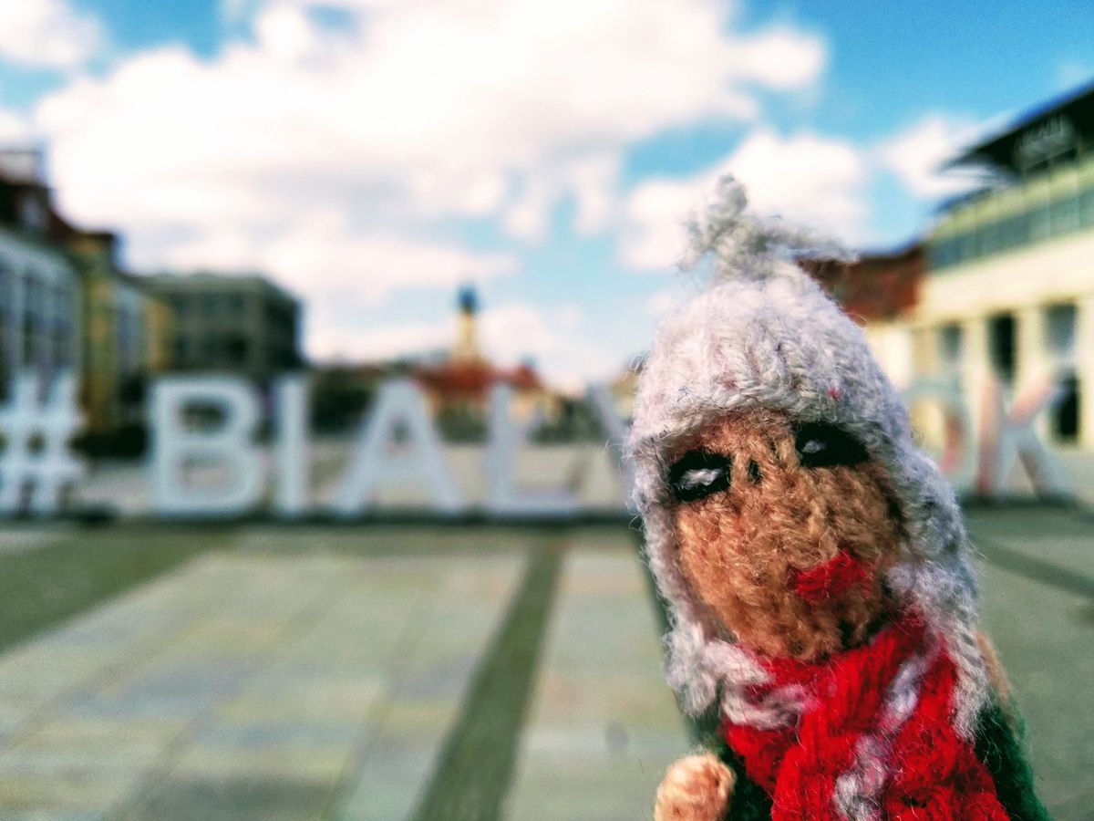 A cute finger puppet poses for a selfie in front of the #BIAŁYSTOK sign.