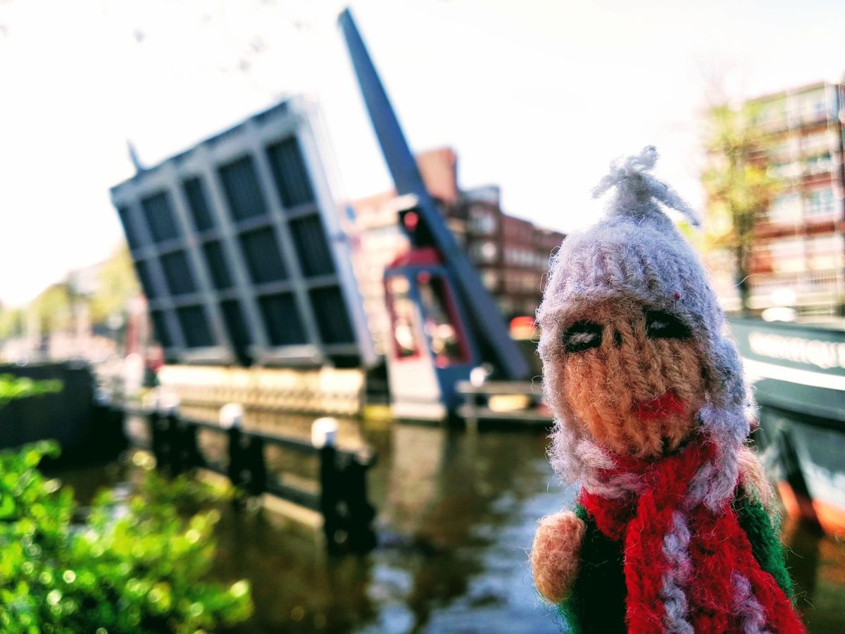 A small Peruvian finger puppet stands pert in front of an erect drawbridge in Amsterdam.