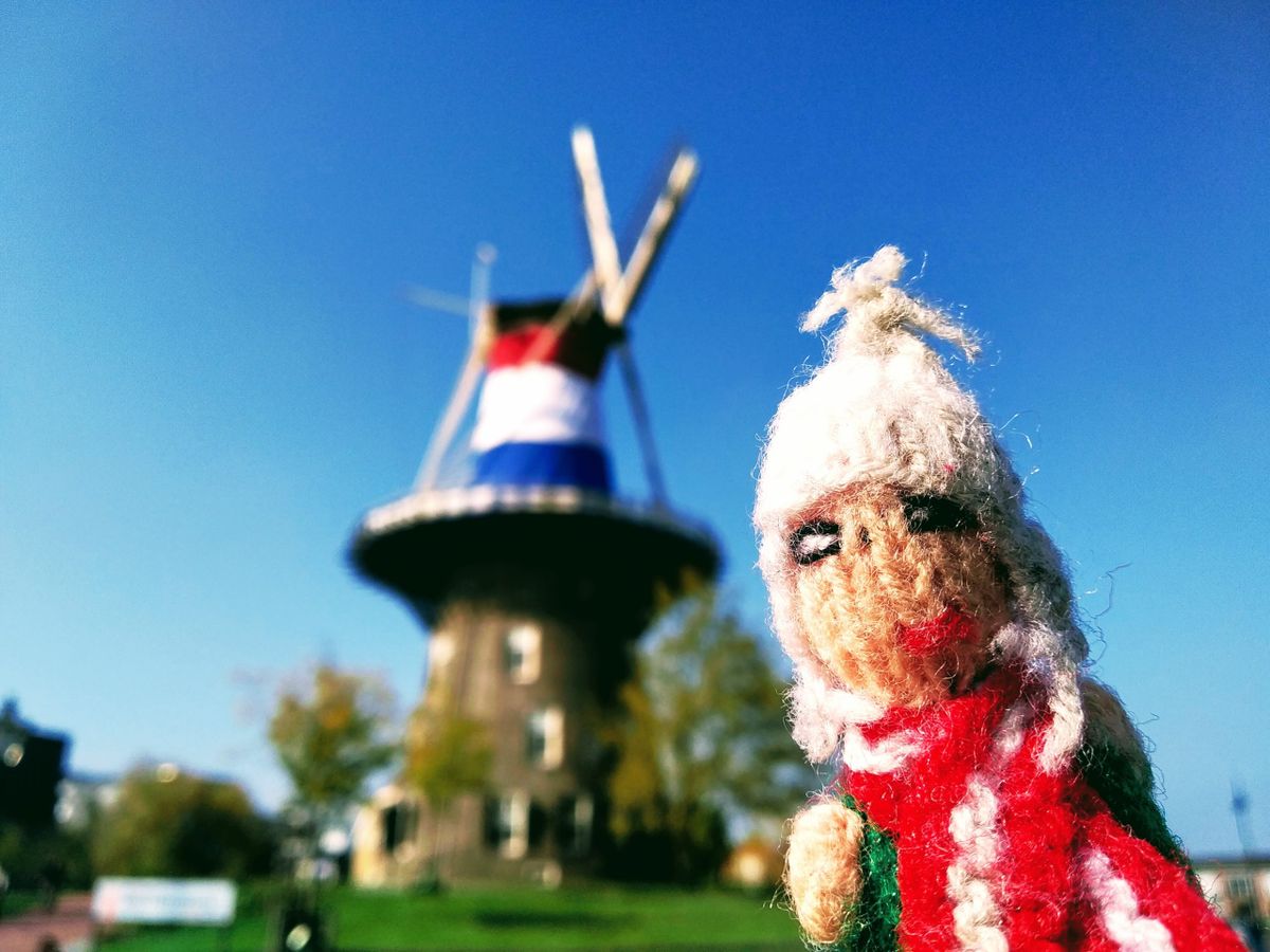 A stupified finger puppet just about holds it together in front of a windmill decorated with the Dutch tricolour.