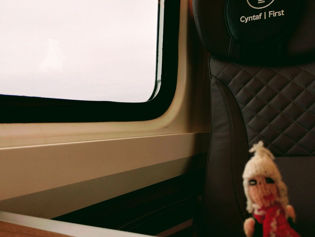 Finger puppet reclines in a sumptuous leather seat in first class on a Transport for Wales train.