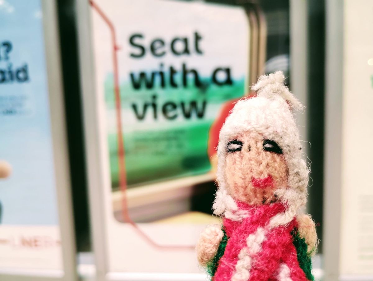 Finger puppet in front a poster of a train window reading "Seat with a view"