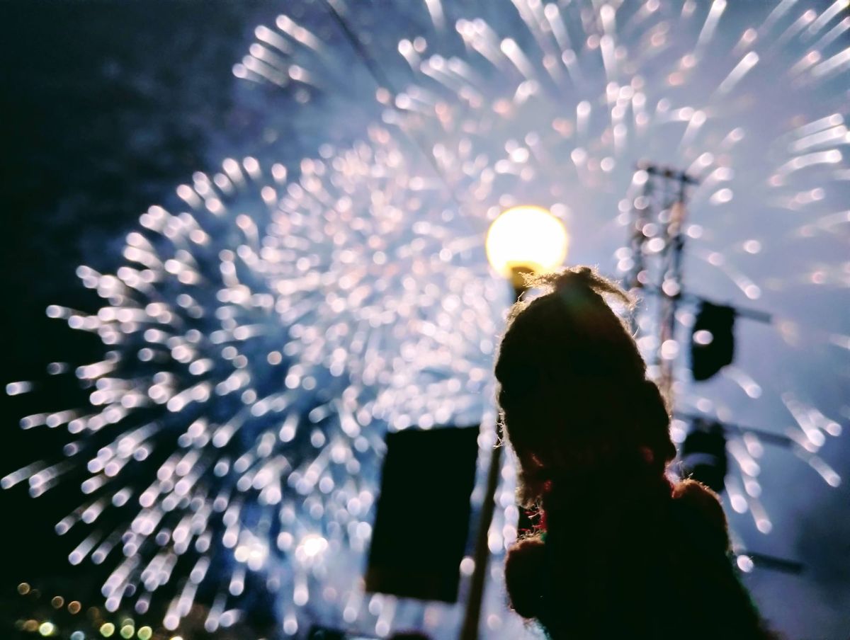 A Peruvian finger puppet in silhouette enjoying white sparkly fireworks.