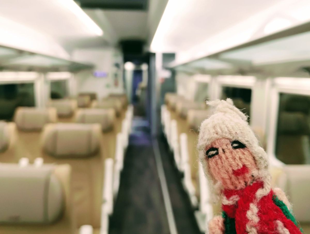 Finger puppet in first class on an Renfe train with tan leather seating in rows.