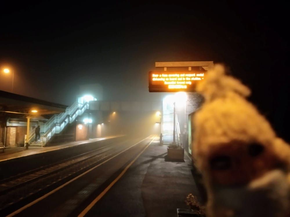 A hardy finger puppet waiting at a train station shrouded with fog.