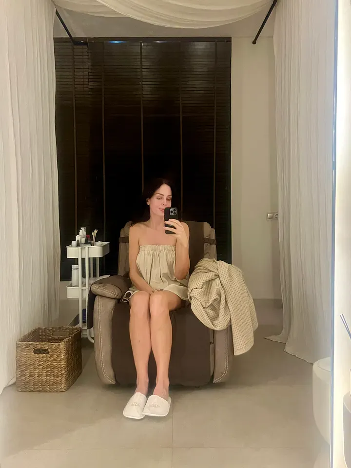 Stevie in a robe taking a mirror selfie in a treatment chair at Face Therapy Spa