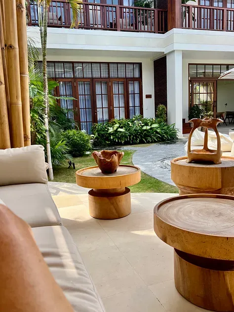 Plawa Laguna courtyard with timber side tables, a sofa and tropical garden in front of the two-storey villa