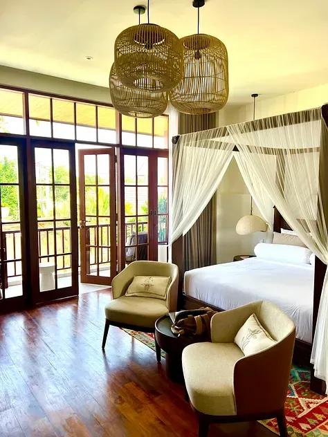 Queen room at Plawa Laguna with a four-poster bed, sheer curtains, rattan pendant lights and French doors to a balcony