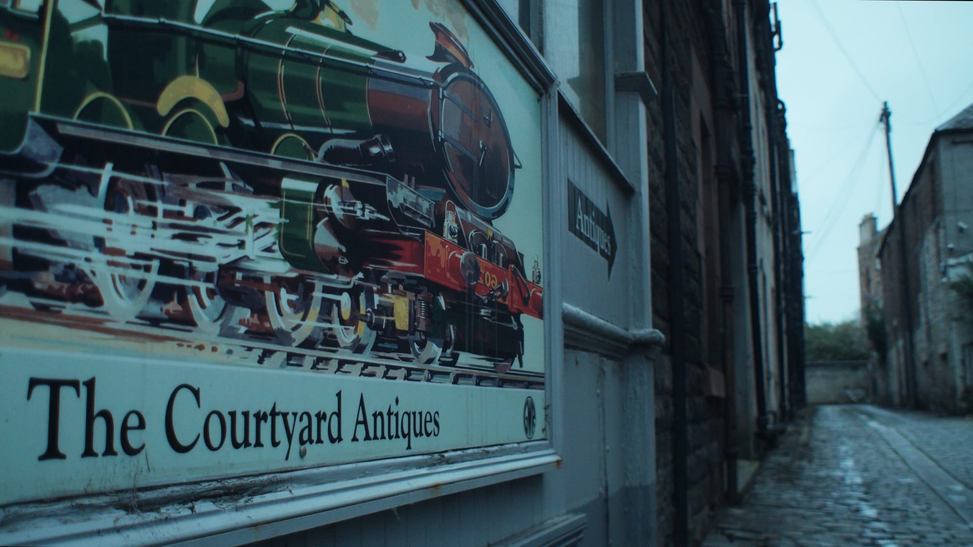 A vintage sign featuring a steam train marks the entrance to Courtyard Antiques, a hidden shop down a quiet cobbled lane in Edinburgh