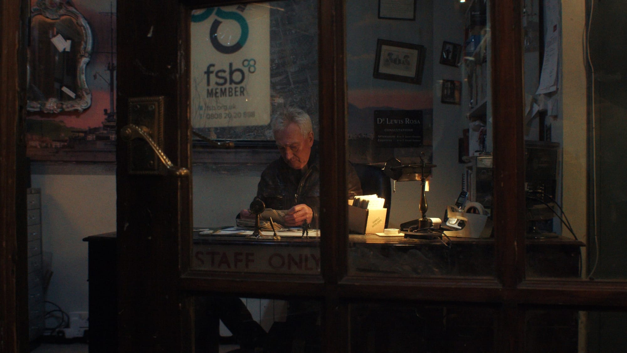Lewis Rosa, owner of Courtyard Antiques, sits in his dimly lit office, sorting through papers behind a glass door marked “STAFF ONLY”