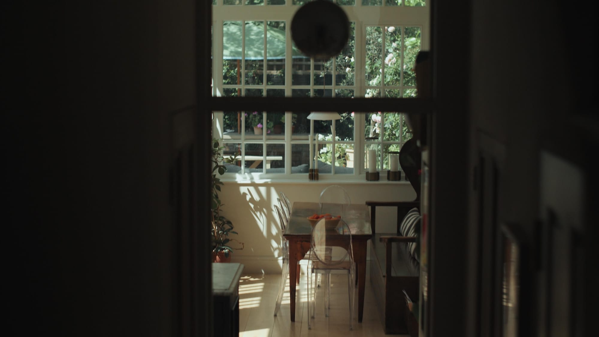 A view down the hallway into a bright dining area with large windows and garden light