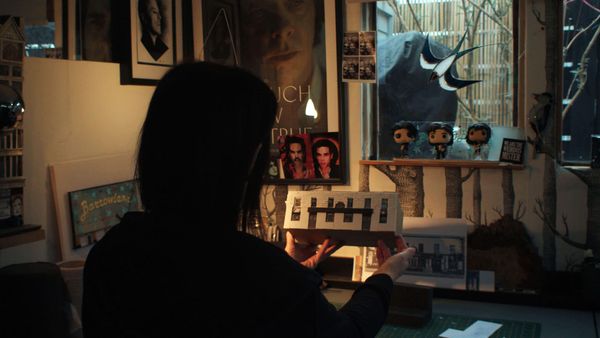 Karen Bones holding a miniature model of a building in a dimly lit room