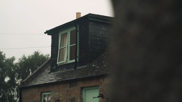 Stone cottage with dark slate roof and a small dormer window with pale green frames