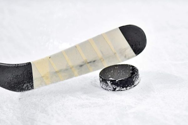 A junior hockey player in a dark road jersey skates along the boards during a Western Hockey League regular-season game.