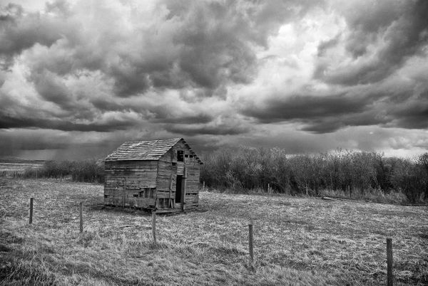Heavy grey clouds spread across a flat Alberta prairie landscape under a dim autumn sky.