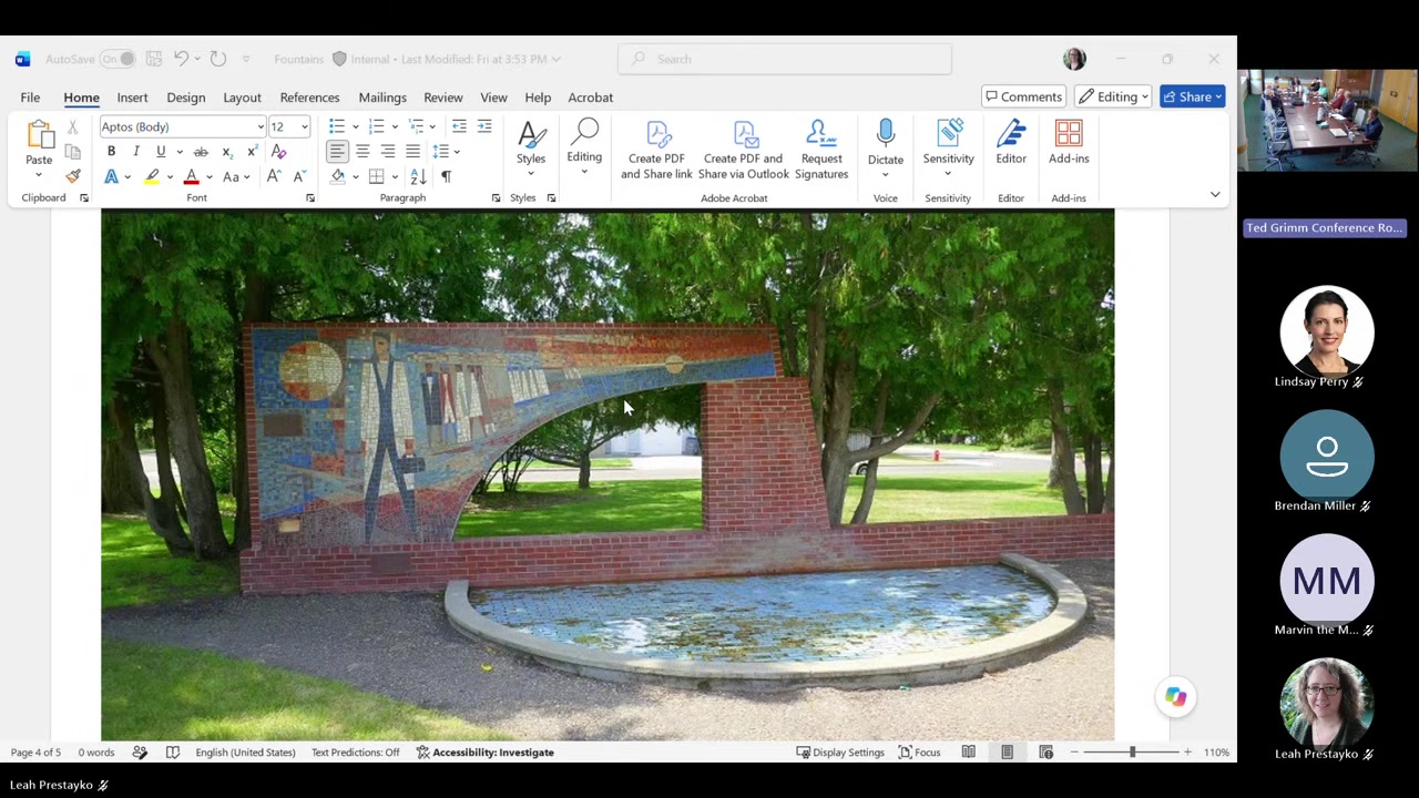 A brick wall mosaic fountain with a dry oval basin at what appears to be Dan McCharles Park in Medicine Hat, surrounded by green trees.