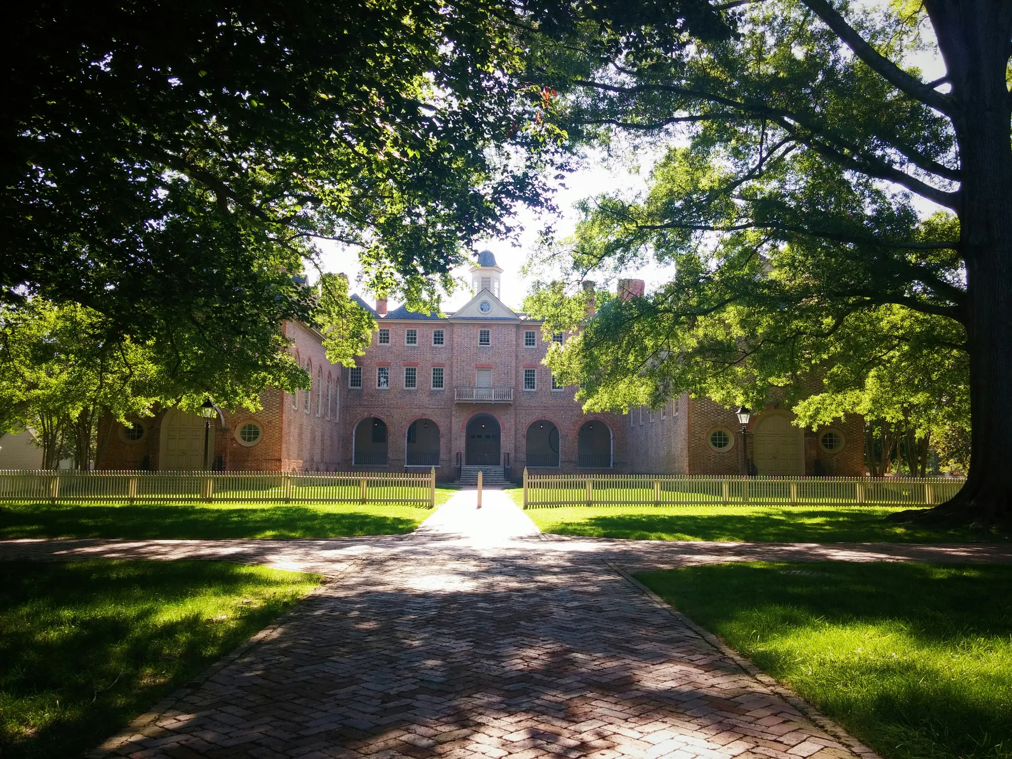 Photograph of the yard of the Sir Christopher Wren building, shaded by ancient oak trees, at the College of William & Mary in Virginia