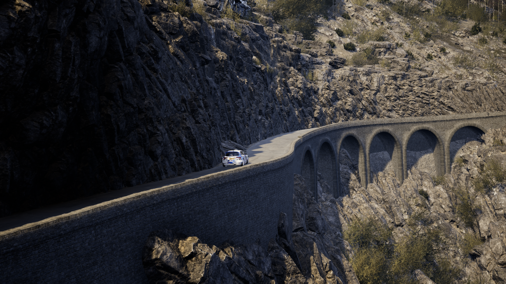 A far away shot of a Skoda Fabia rally car on a paved, cliffside road.