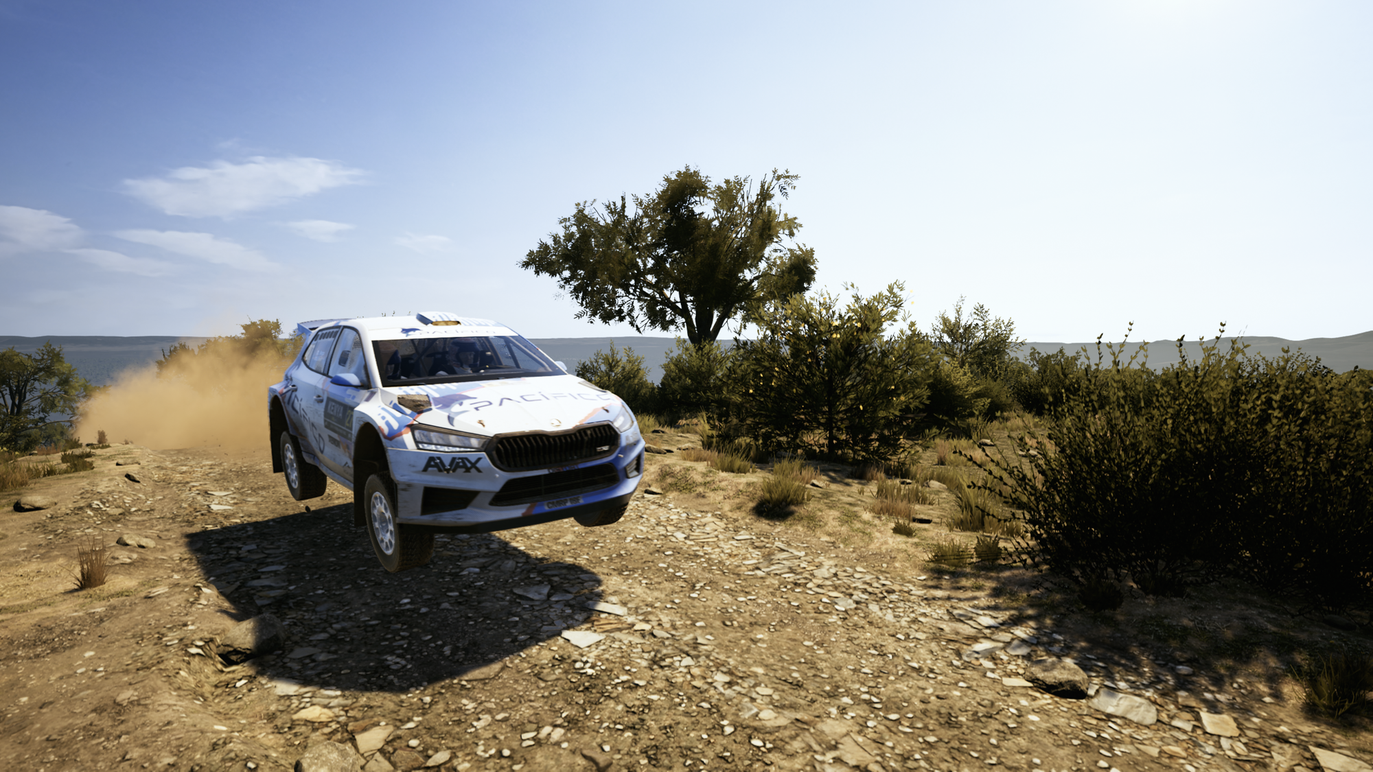 A Skoda Fabia rally car mid-jump after it crested a hill in the African plains.