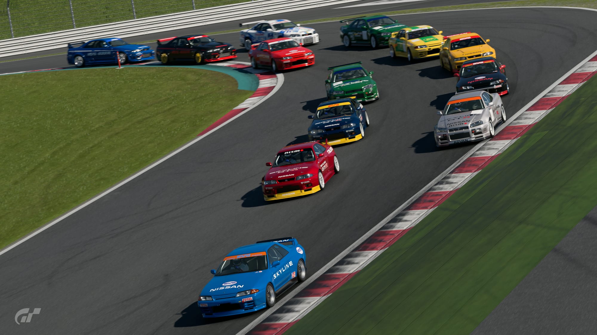 Thirteen Nissan Skyline GT-Rs navigate the first turn at Fuji Speedway. With the exception of the Nurburgring 24 Hour-styled R34 in the back, all of these cars were modified to resemble the race modifications the cars would have had in the first two Gran Turismo games with very basic racing liveries.