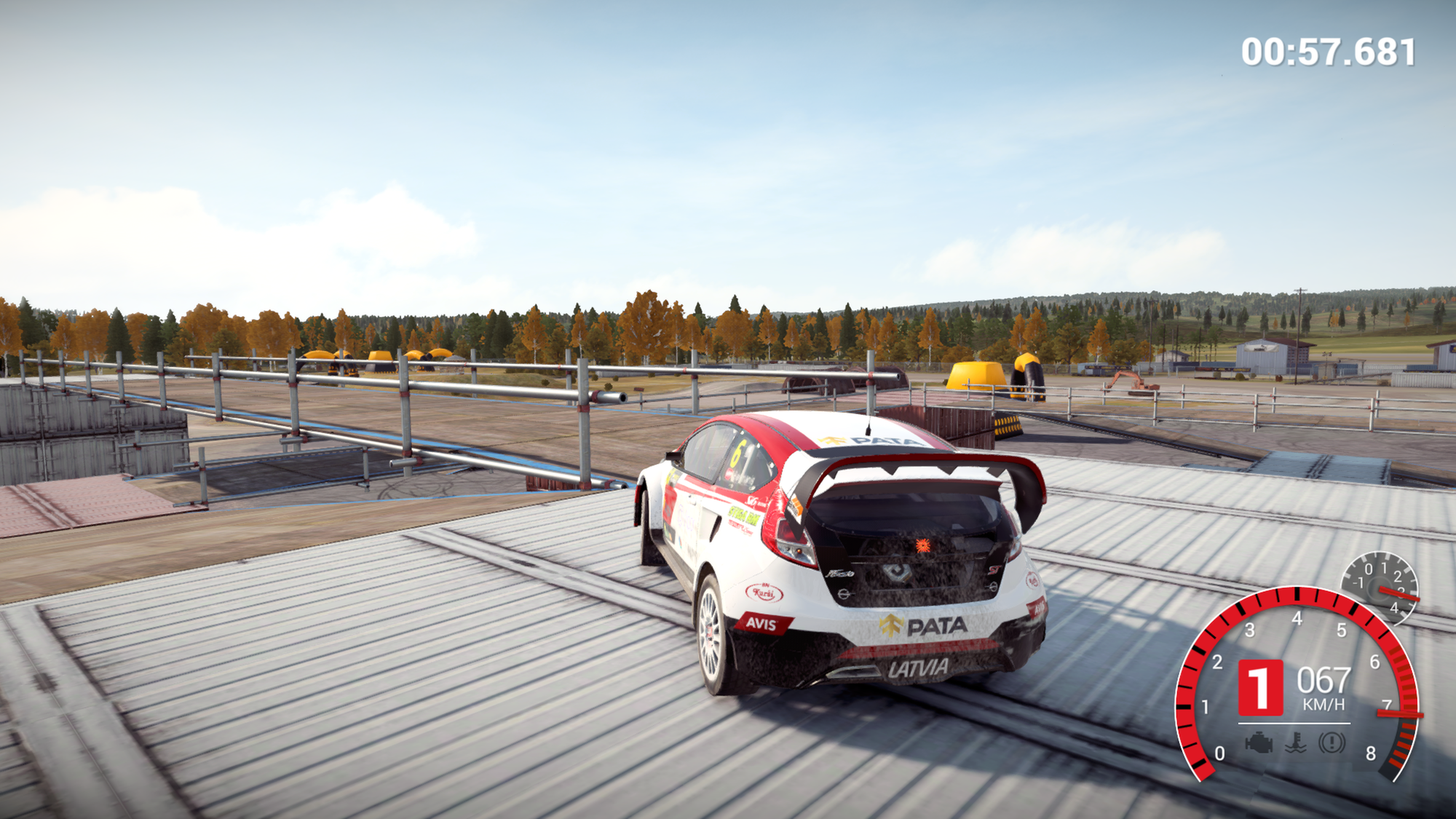 A Ford Fiesta Rallycross supercar navigates a scaffold and shipping container structure at speed at the DirtFish facility in DiRT 4.