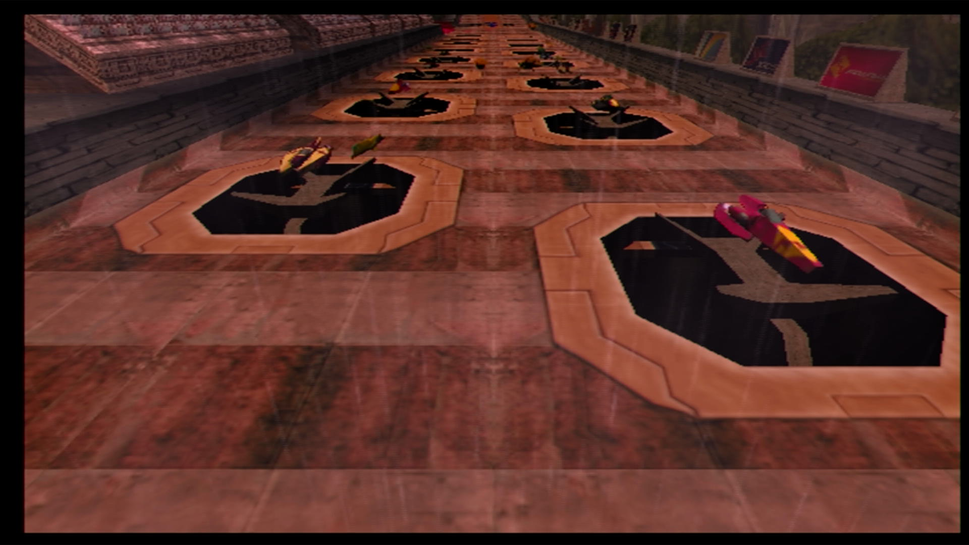 Looking back at the starting grid for a race in Wipeout Fusion, with the red and yellow Pirhana and maroon and gold Xios on the front row of the grid.