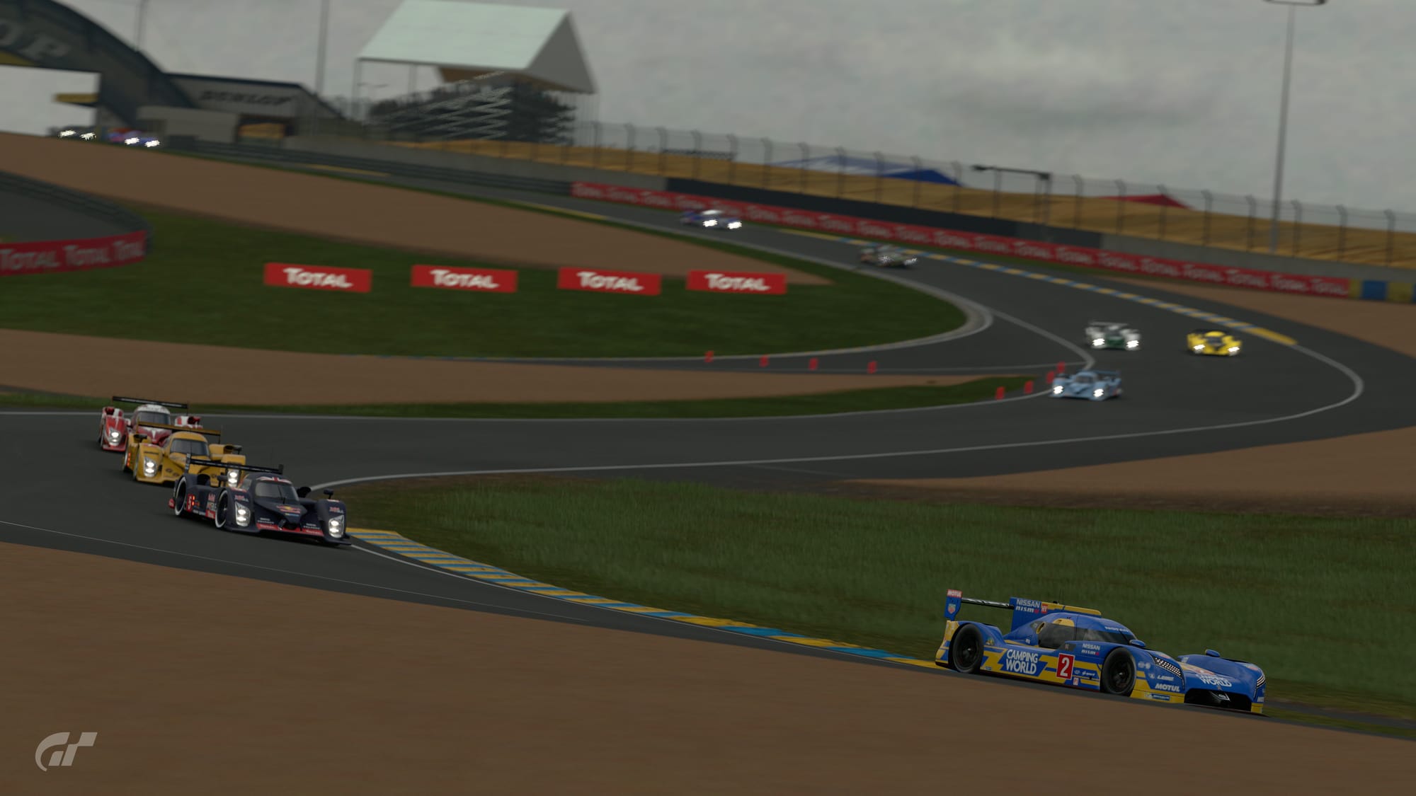 A blue and yellow Camping World sponsored Nissan GTR LM Nismo leads the field of Le Mans Prototypes through the esses at Le Mans.