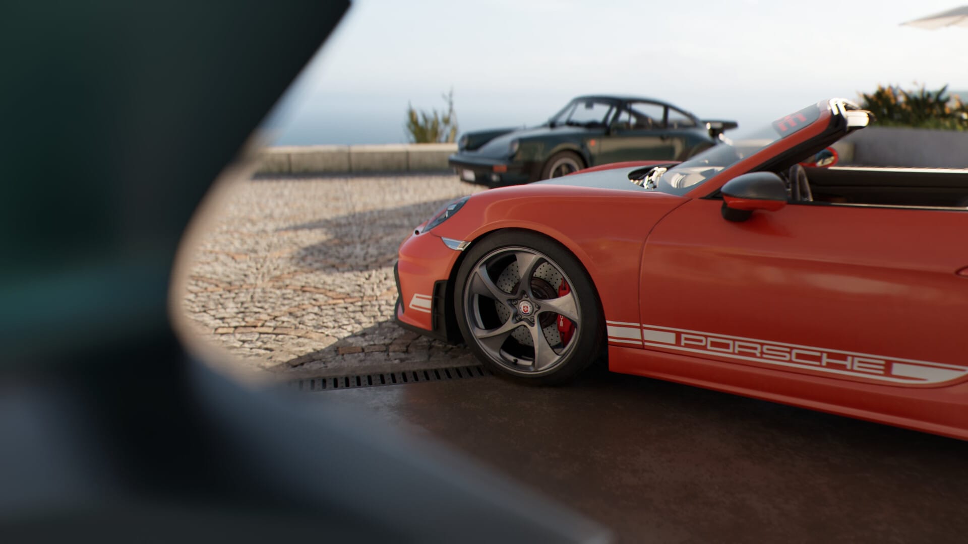 A pair of Porsche 911s parked in a cobble driveway, a more modern red one on the foreground and a classic black 911 Turbo in the background.