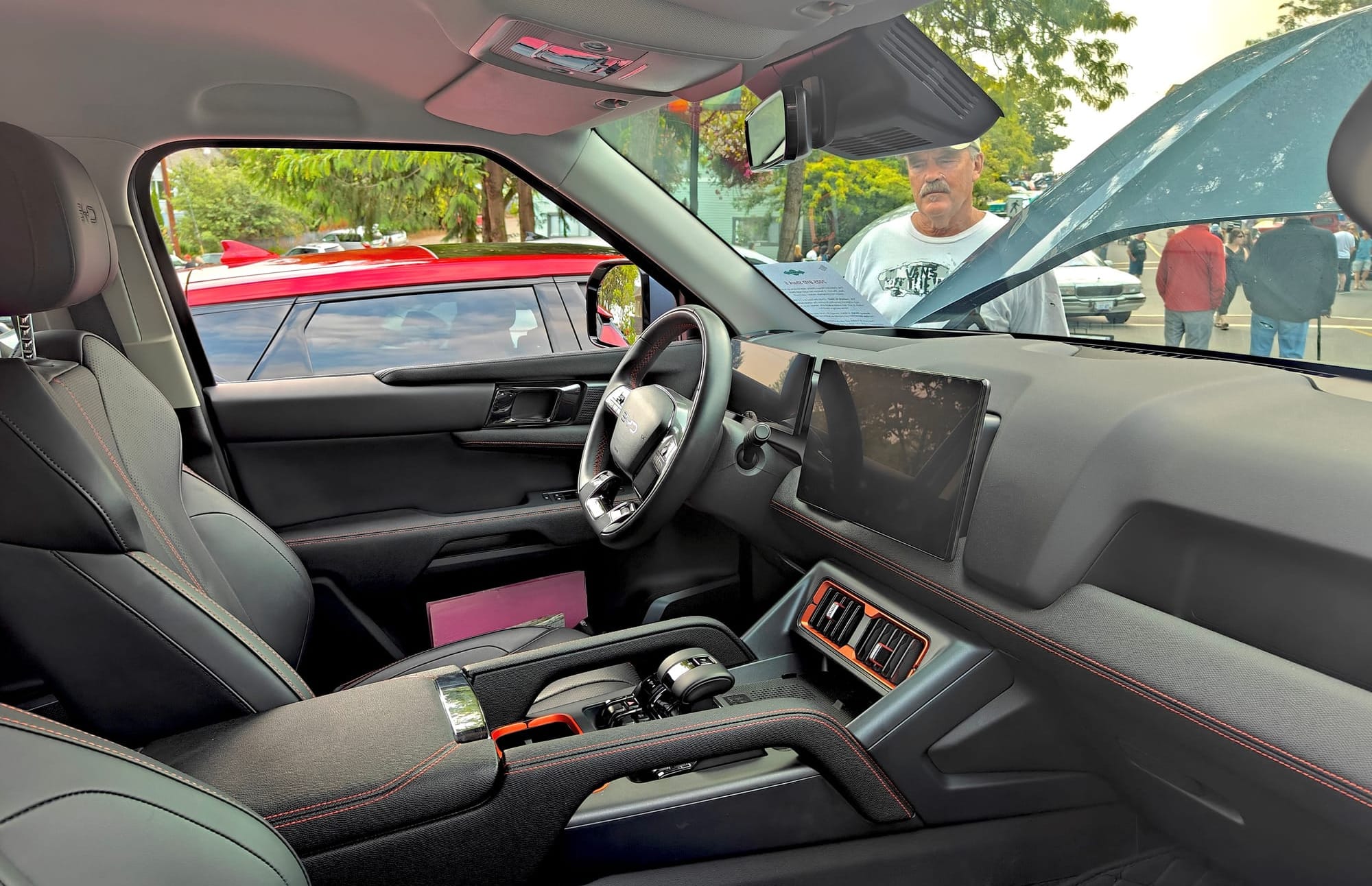 The interior of the BYD Shark 6, with orange stitching and surrounds to the central venting and cupholders..