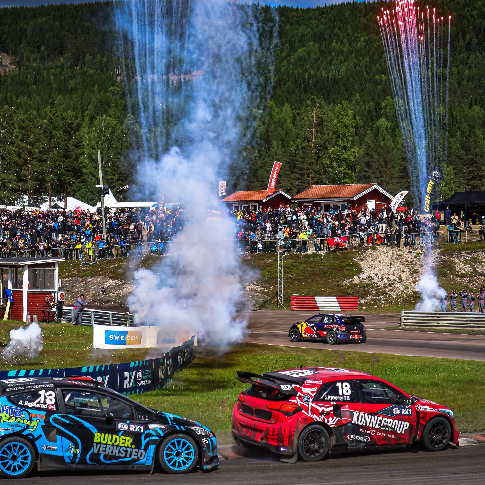 Johan Kristoffersson crosses the finish line first at Höljes, Sweden in the background, with Andreas Bakkerud and Juha Rytkönen in the foreground on the opposite end of the final corner.