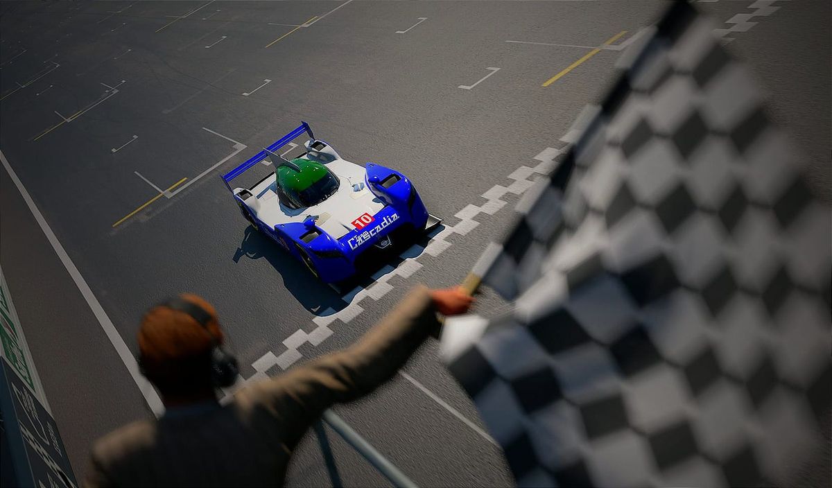 A blue, white and green Nissan GT-R LM NISMO race car crossing the finish line at a race, from the perspective of the flag man.
