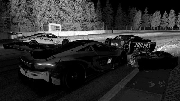 A black and white screenshot of a Ferrari 488 GT3 being run into by a McLaren 720S GT3, as another McLaren drives by to their left.